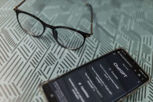 ChatGPT on mobile phone on desk with eyeglasses